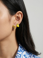 Close-up of a person wearing a yellow floral earring with a gray background