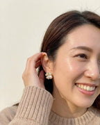 Woman wearing pearl earrings with a neutral background