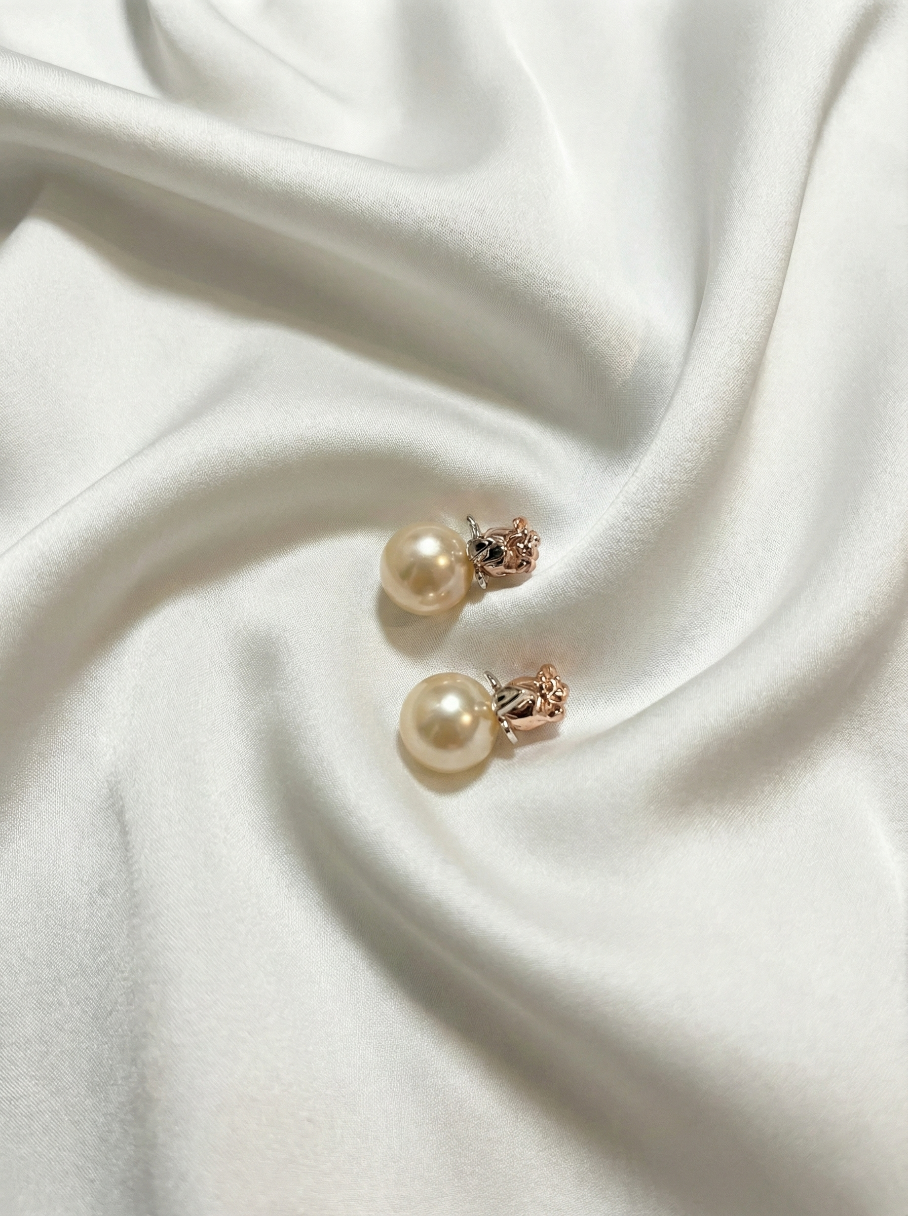 Pearl earrings on a white fabric background by SFUMATO