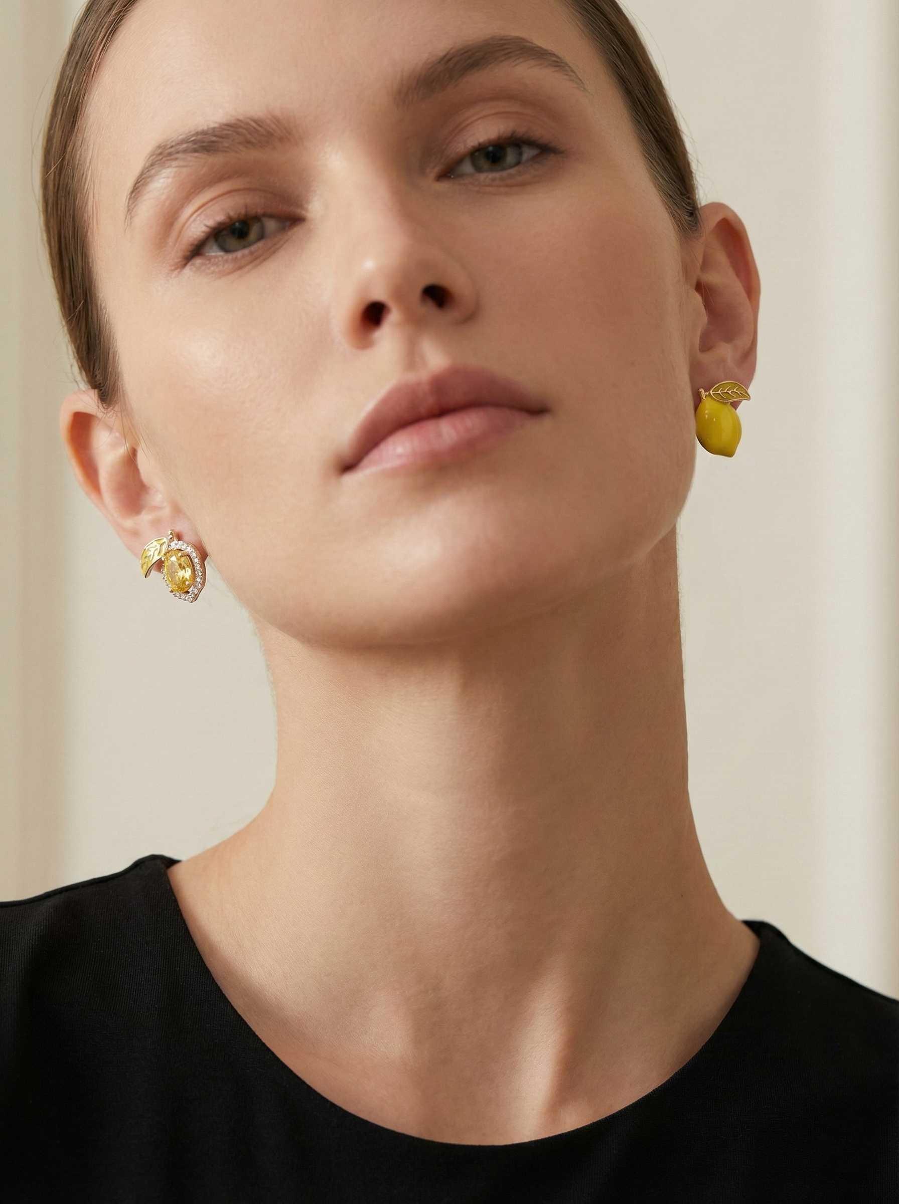 Close-up of a person wearing gold earrings with a neutral background