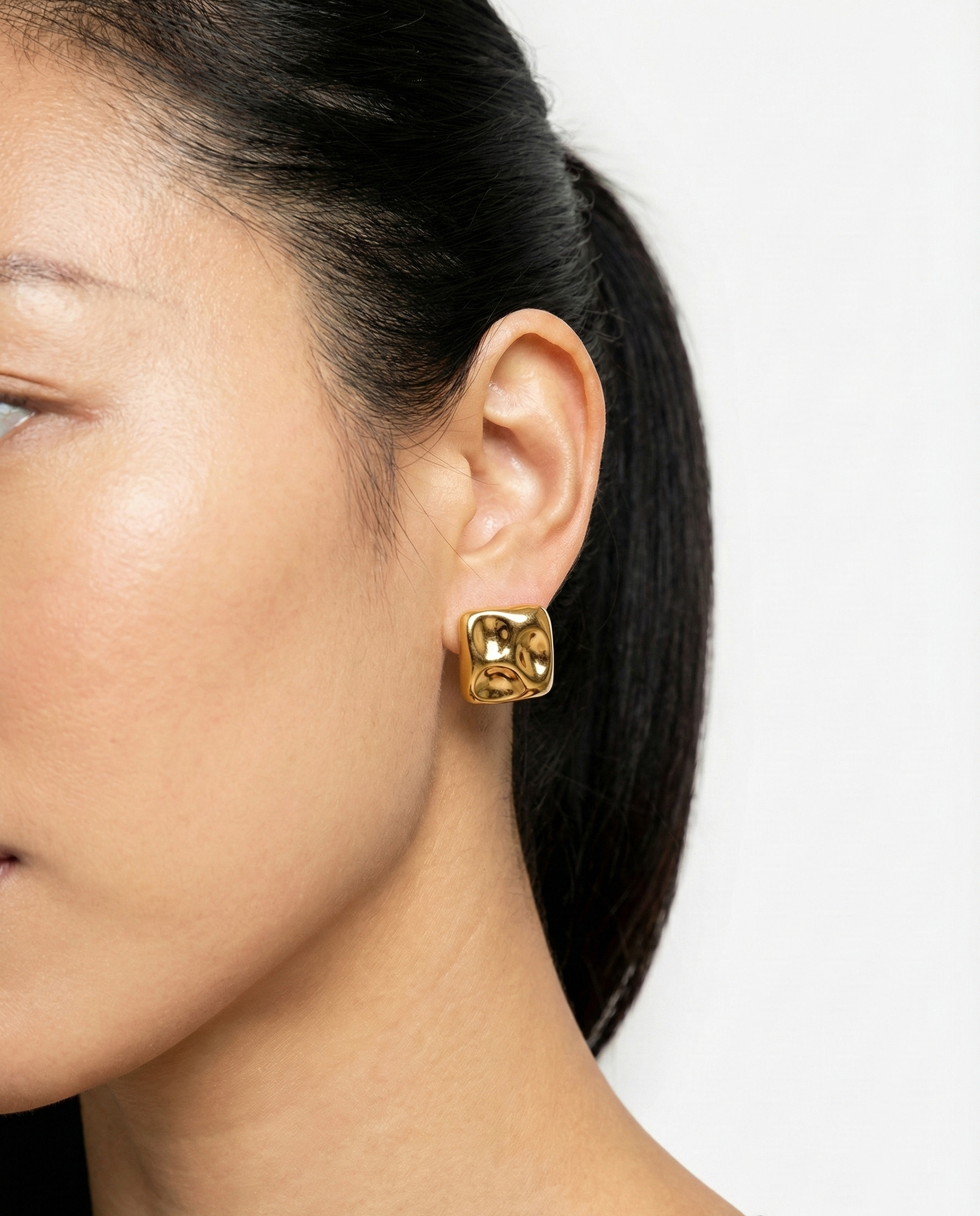 Gold earring worn by a person on a white background by SFUMATO