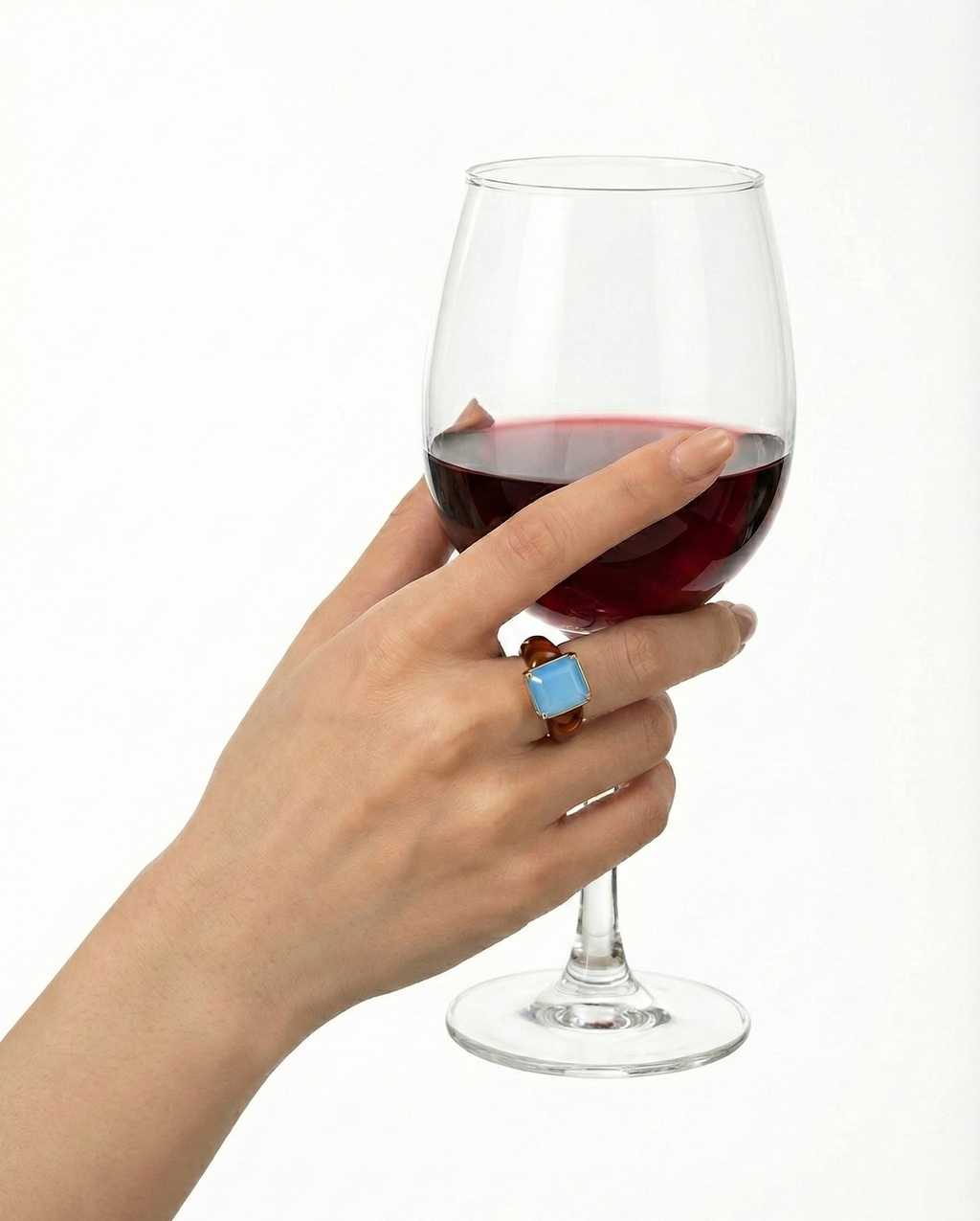 Hand holding a glass of red wine with a blue ring on a white background
