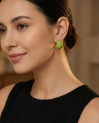 Woman wearing green earrings with a blurred background