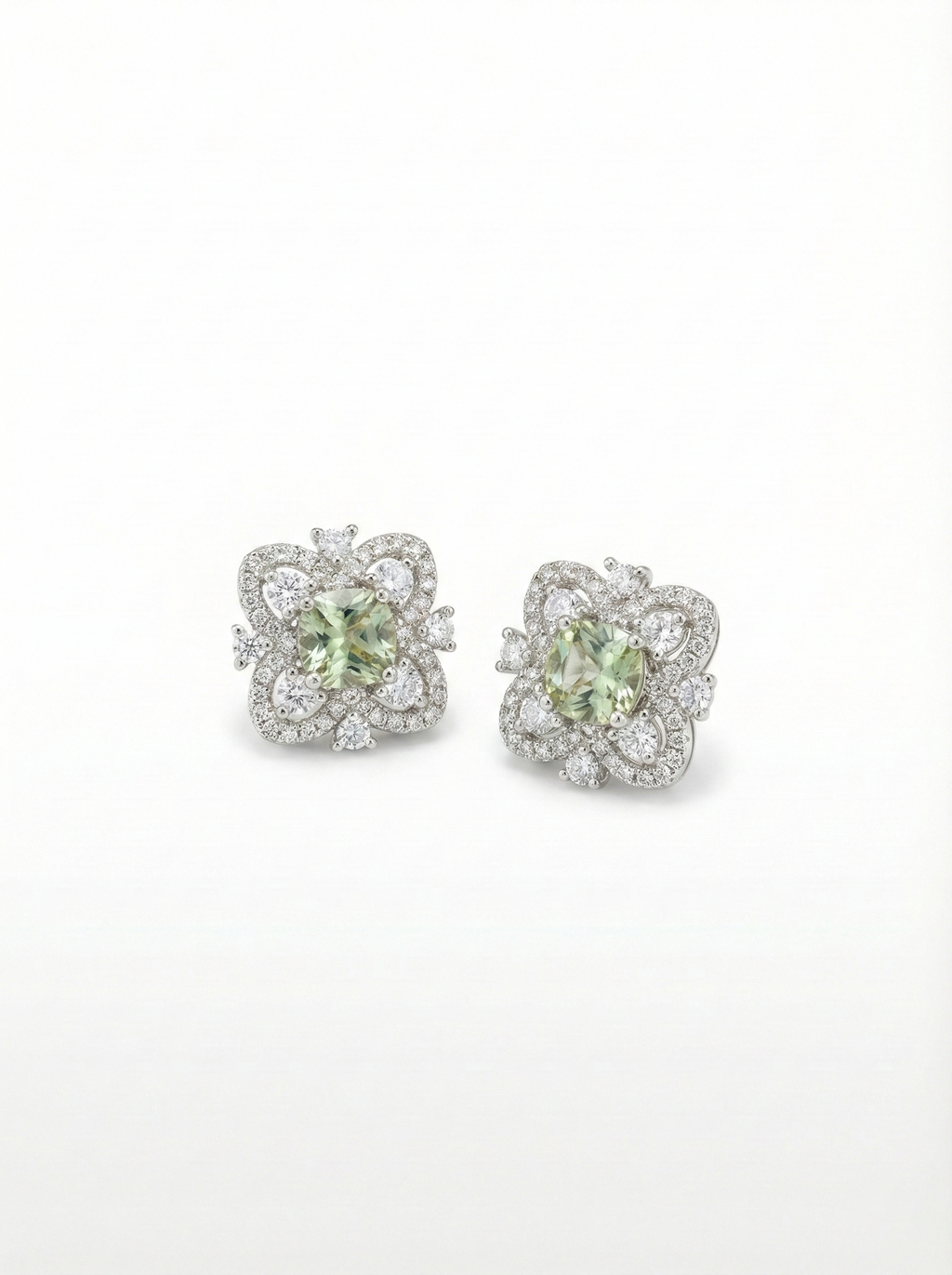 Pair of earrings with green gemstones and diamond accents on a white background