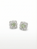 Pair of earrings with green gemstones and diamond accents on a white background