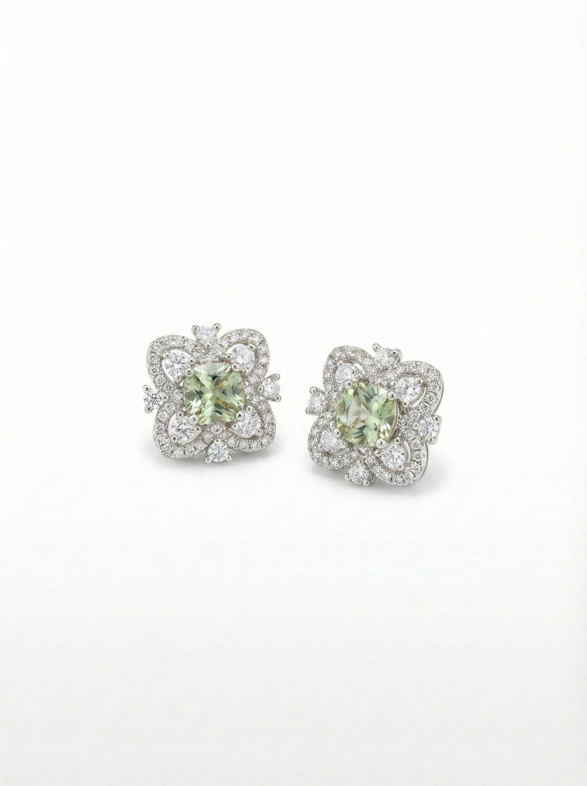 Pair of earrings with green gemstones and diamond accents on a white background by SFUMATO