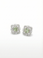 Pair of earrings with green gemstones and diamond accents on a white background