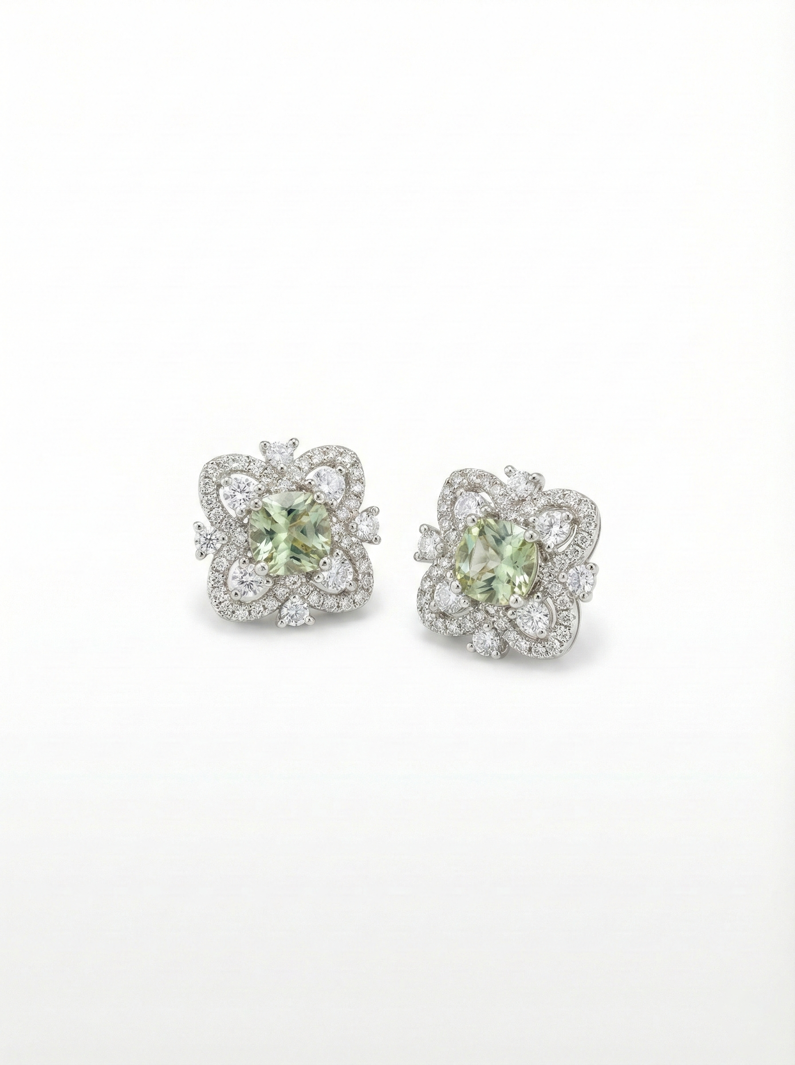 Pair of earrings with green gemstones and diamond accents on a white background
