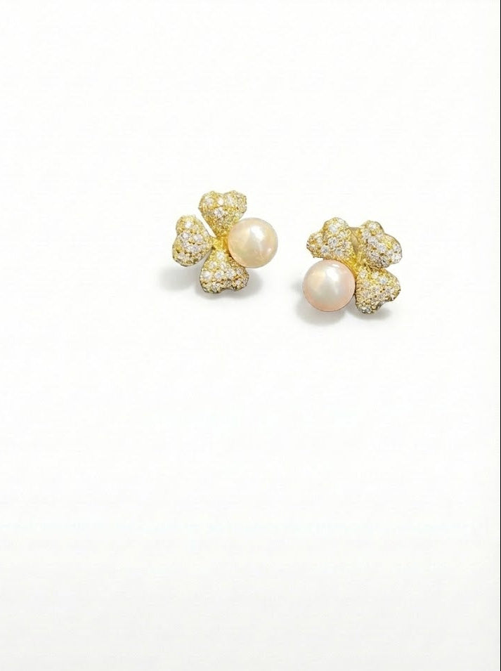 Pair of pearl earrings with gold accents on a white background by SFUMATO