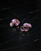 Pair of purple earrings with gold accents on a dark surface