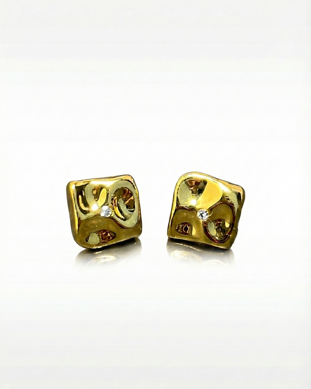 Pair of gold dice-shaped earrings on a white background