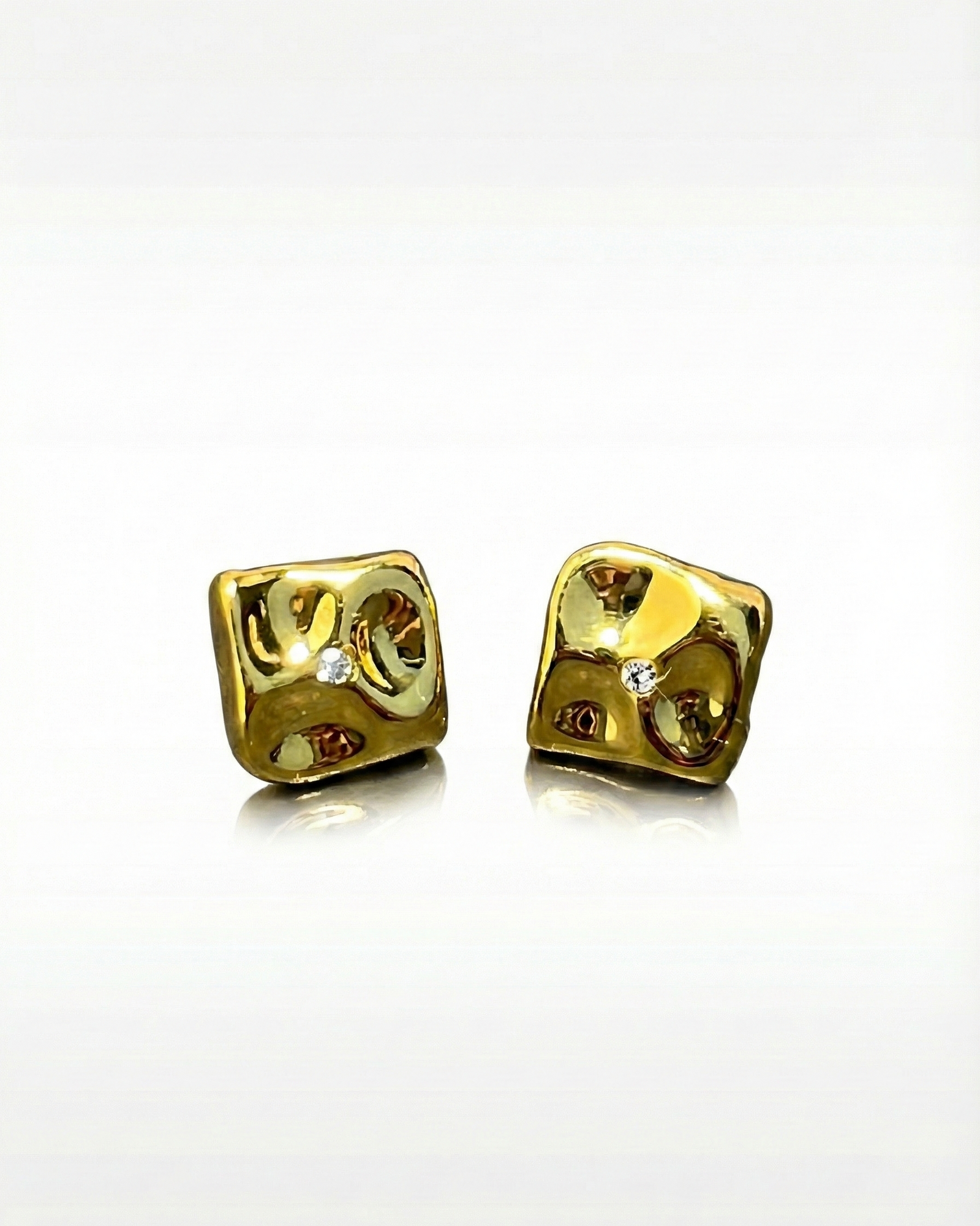 Pair of gold dice-shaped earrings on a white background