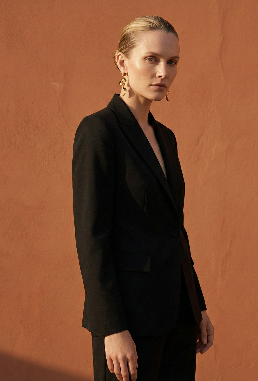 Woman wearing a black suit against an orange background
